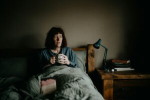 Tired woman sitting awake on the edge of her bed at night